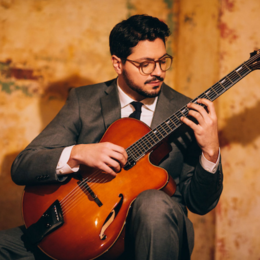 Photo of Pasquale Grasso sitting playing his guitar