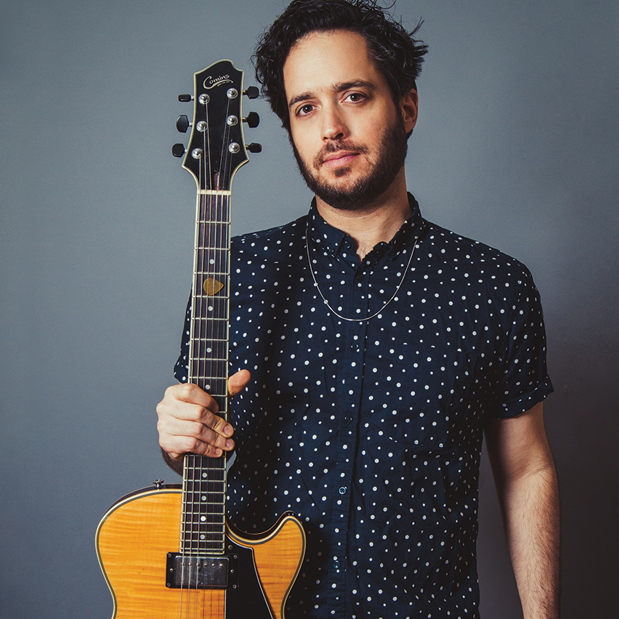 Sam Yahel holding his guitar