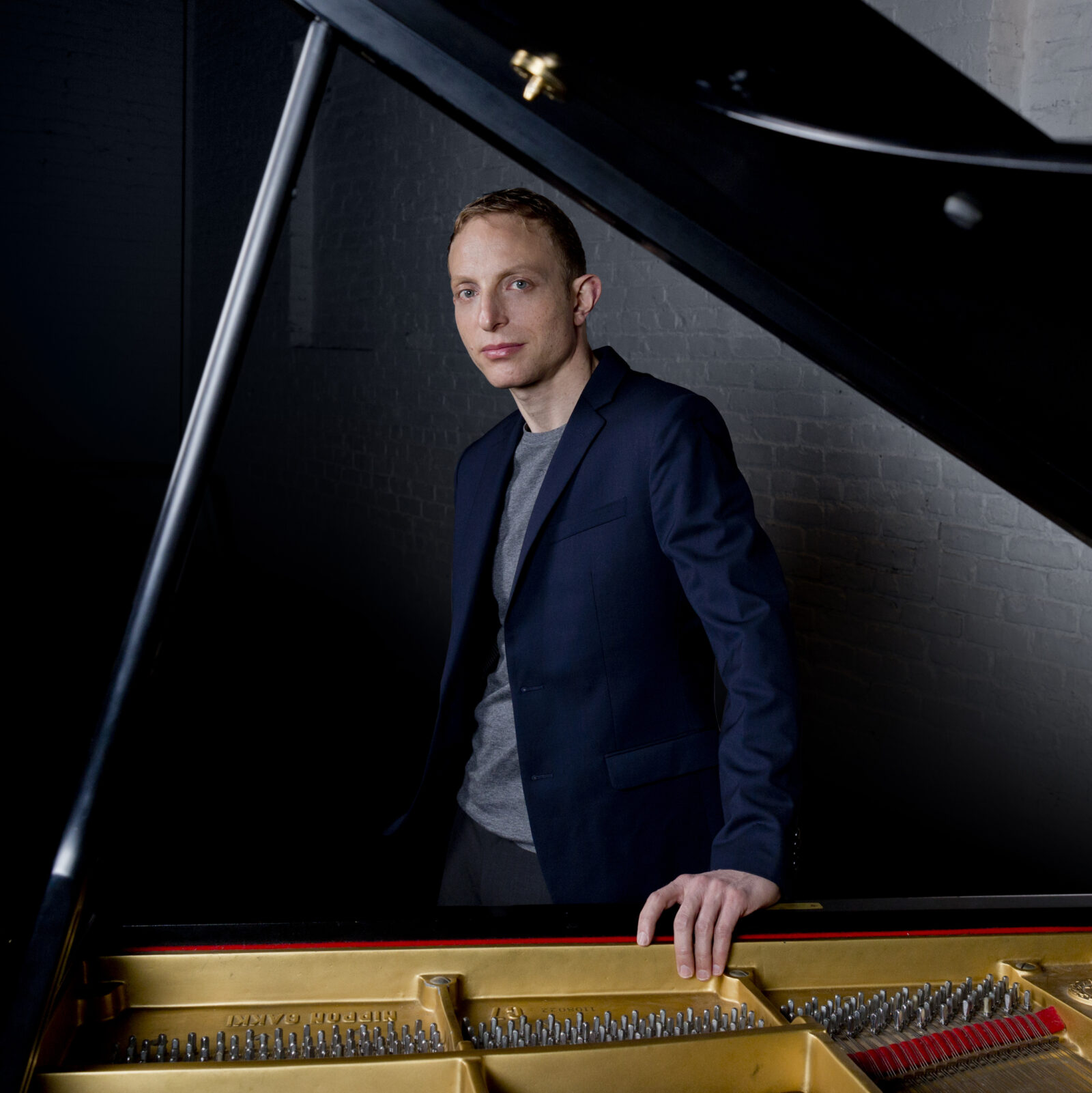 Portrait of a man leaning on an open grand piano