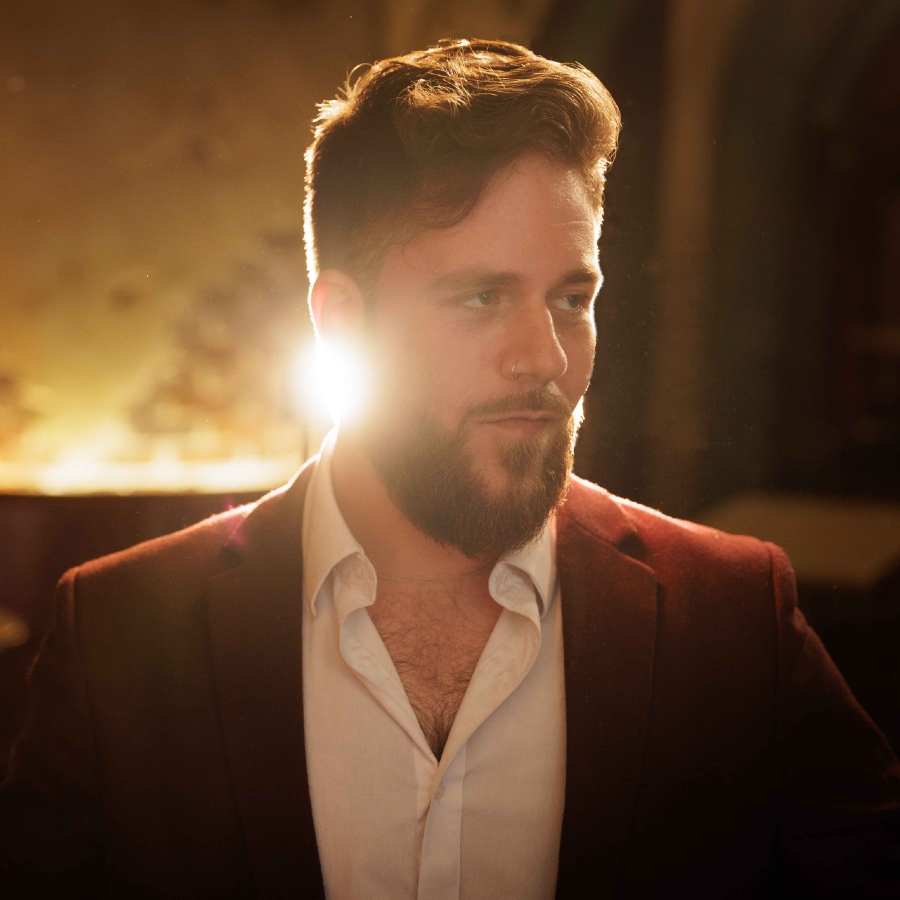 Close up of musician Eitan Kenner with spotlight shining behind him at The Django.