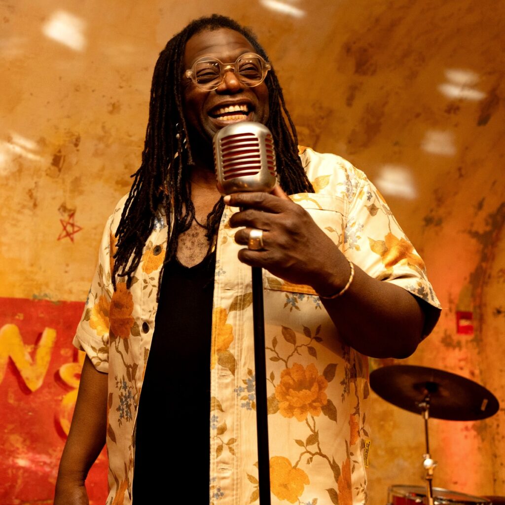 Musician Darnell White Singing onstage holding a vintage mic.
