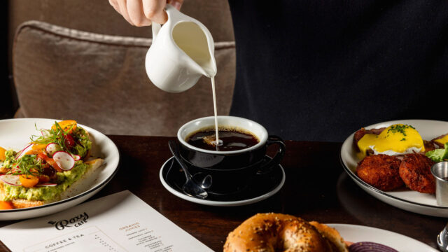 Roxy Café TriBeCa morning breakfast service featuring hot drip coffee, an everything bagel, and a printed menu on a dark wood table.