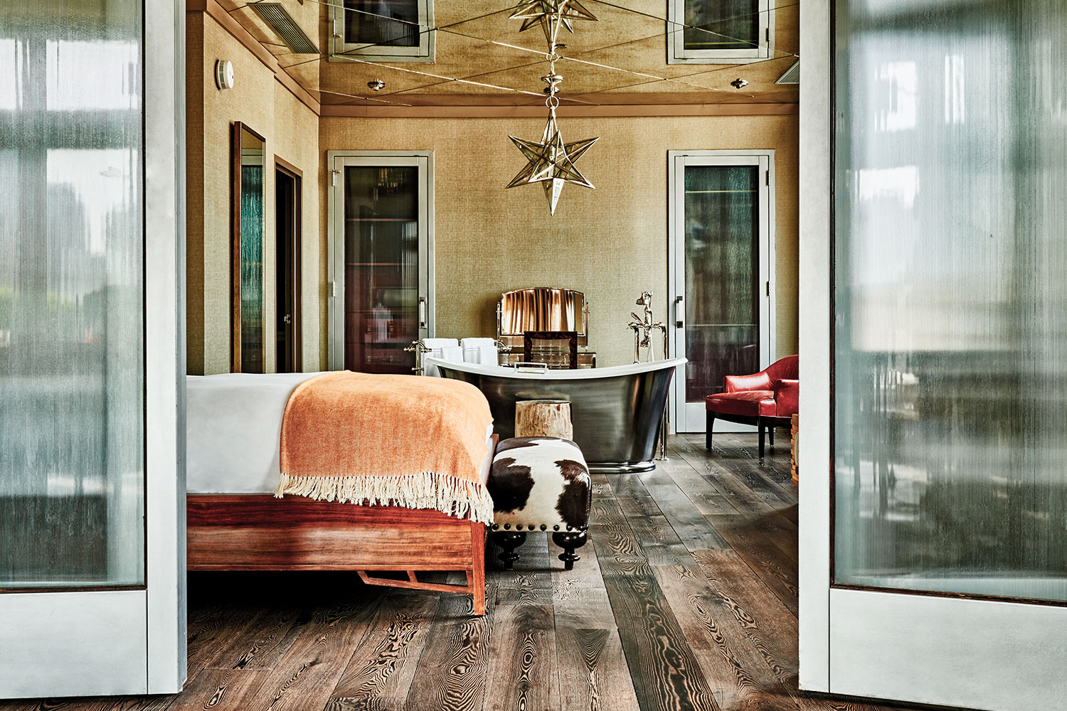 Interior view of the Soho Grand's Loft South room. There is a bed, cow-printed foot stool, and a steel free-standing bathtub