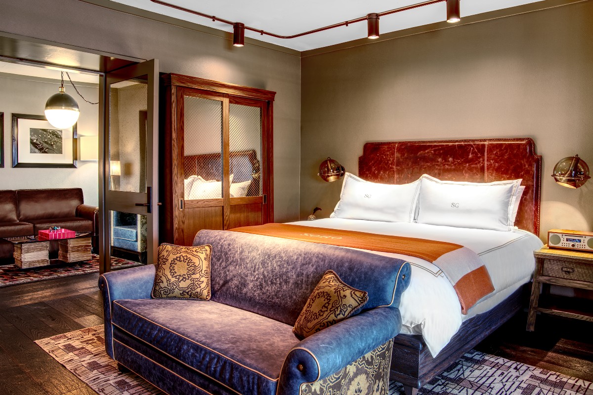 Grand Terrace Suite Master Bedroom with a large bed with an orange throw blanker and a plush couch at the foot of the bed
