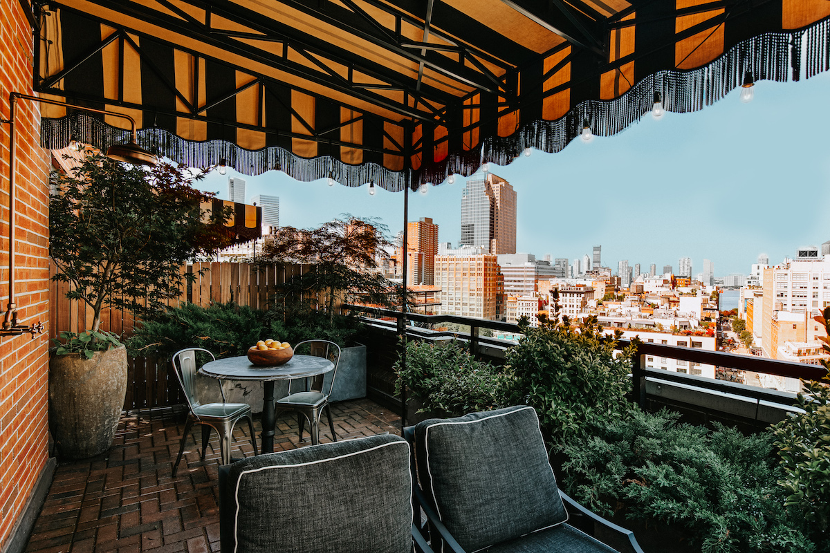 the outdoor terrace with a table and couch covered by a striped awning. overlooks the neighborhood of SoHo