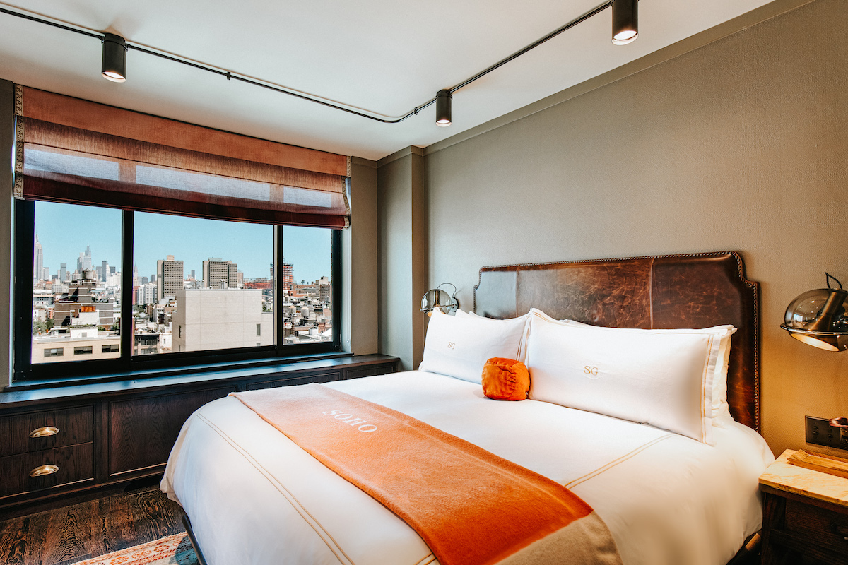 terrace suite master bedroom. there is a king size bed with an orange throw blanket