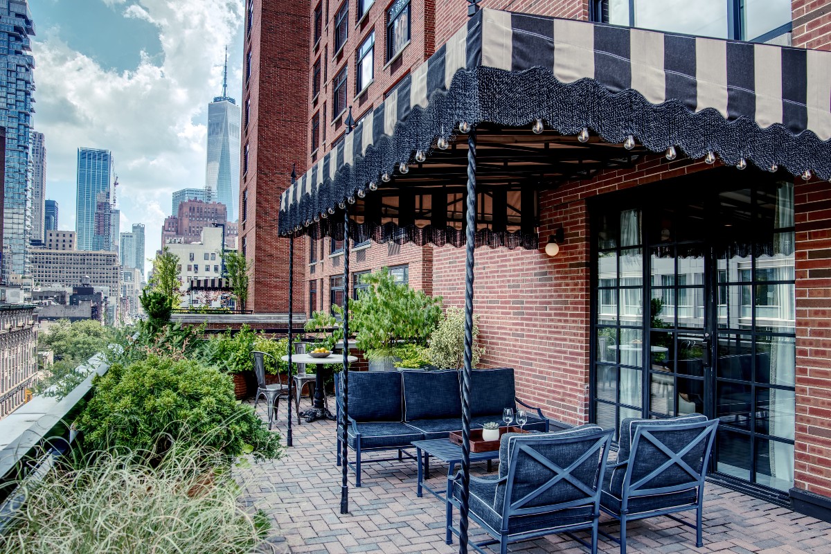 Grand Terrace Suite Blacony with seating covered by a striped awning overlooking downtown manhattan
