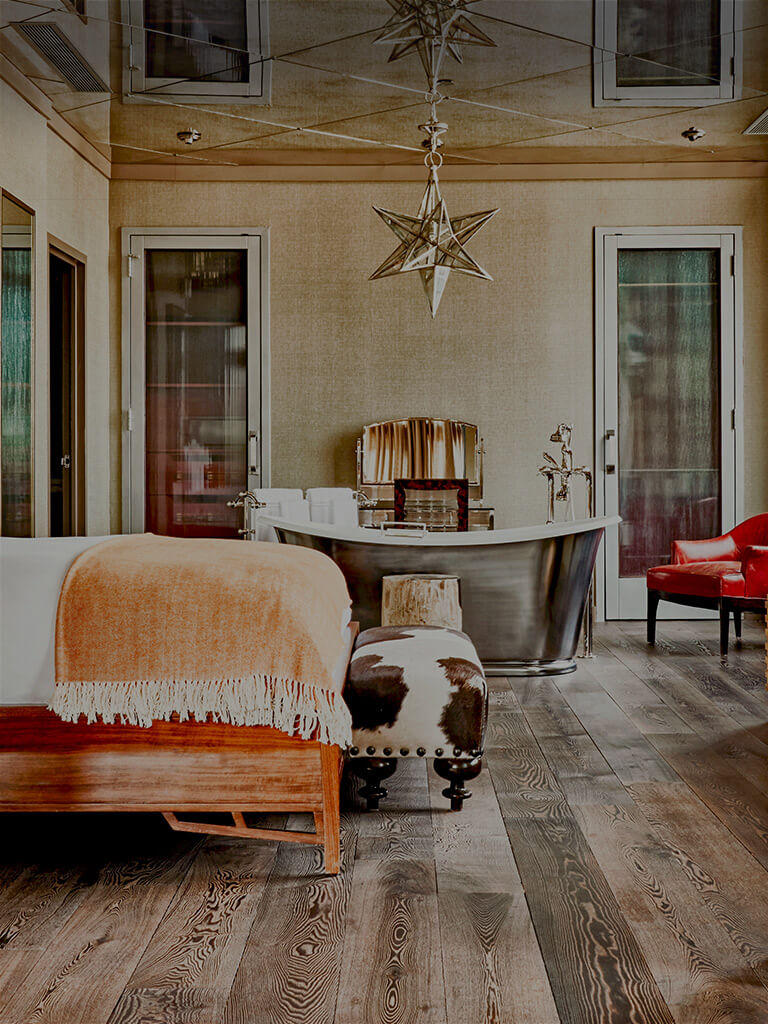 Interior view of the Soho Grand's Loft South room. There is a bed, cow-printed foot stool, and a steel free-standing bathtub