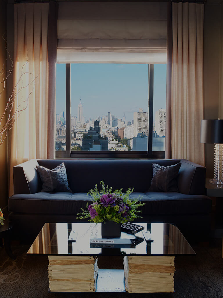 View from the Soho Grand One Bedroom Suite. There is a blue couch and a coffee table in the living with flowers on it