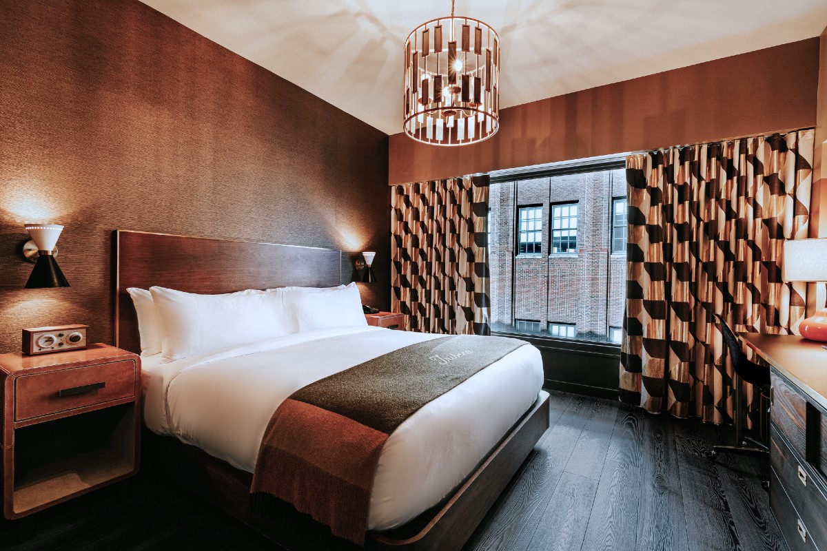Roxy Hotel New York guest room picture showing bed, chandelier and side table.