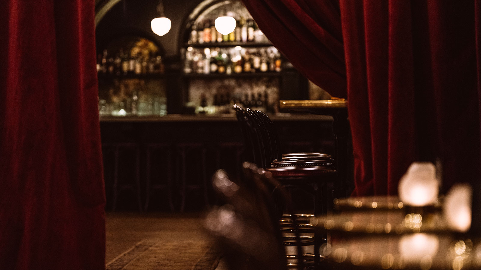A red curtain is pulled back to reveal a bar at The Django in Roxy Hotel.