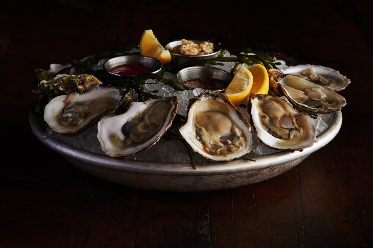 Fresh oysters on ice served at The Oyster Bar at The Roxy Hotel New York, presented with lemon and cocktail sauce.