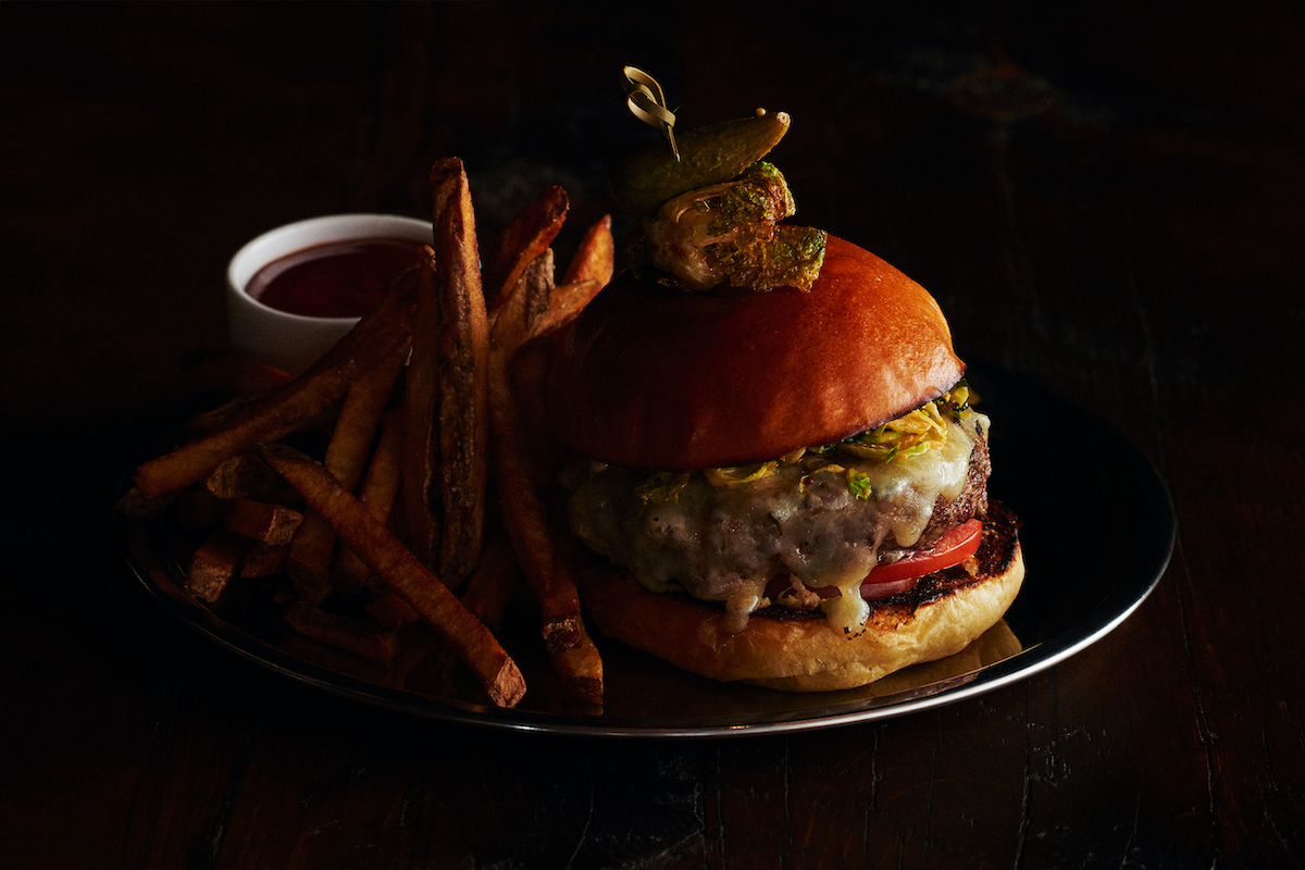 large burger topped with a pickle and served with fries and ketchup