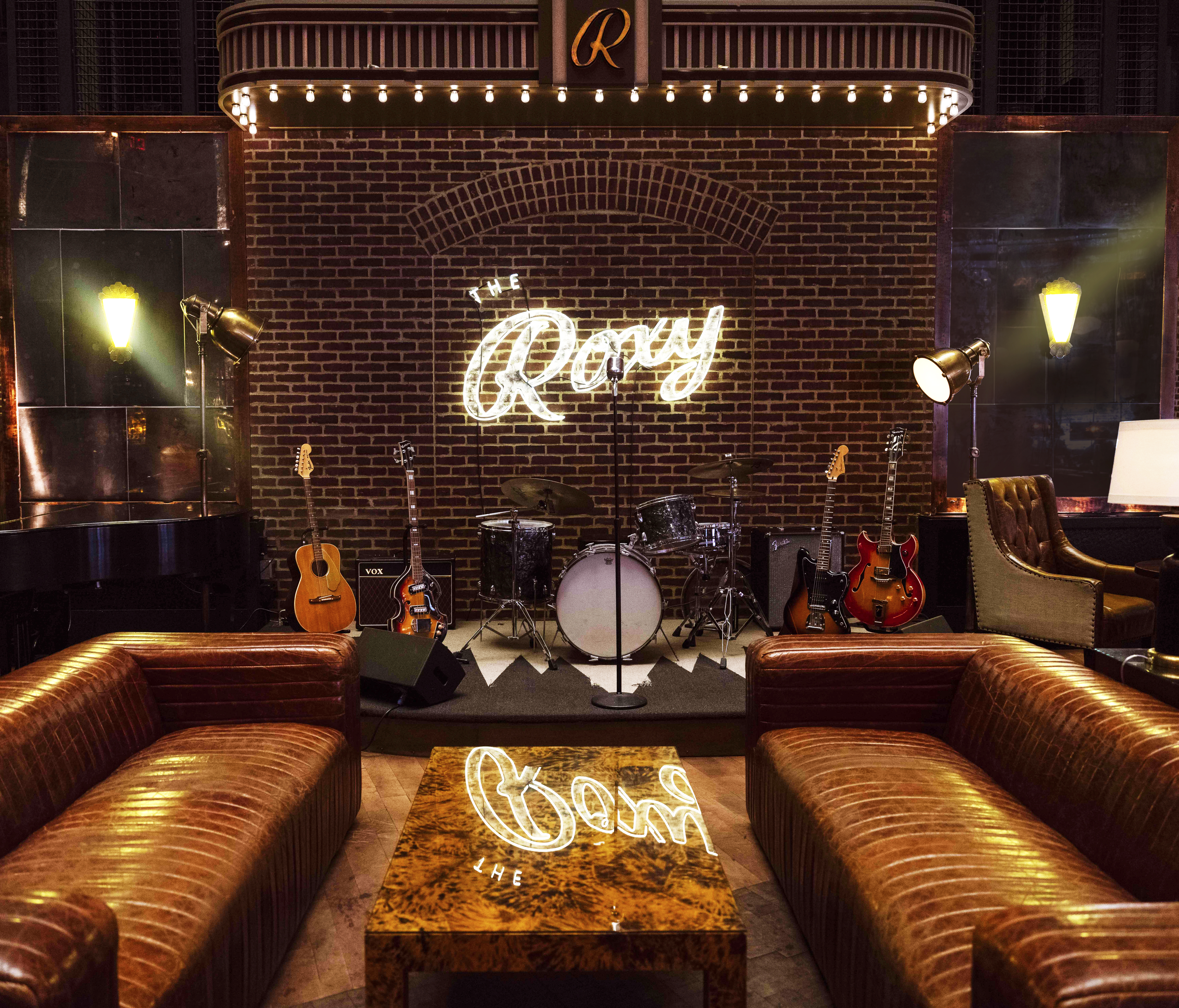 The Roxy Bar stage with guitars and a drum set sitting on stage