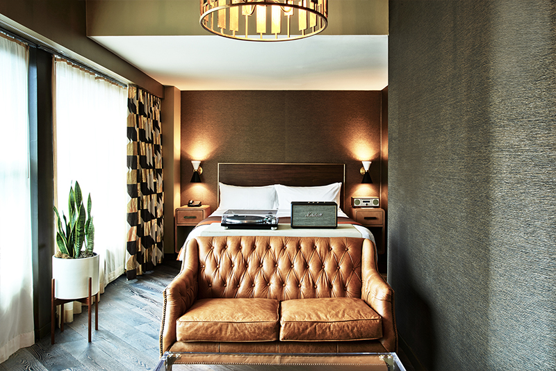 Loft suite bedroom with a king size bed and a leather couch. There is a marshall speaker and turntable sitting on the bed