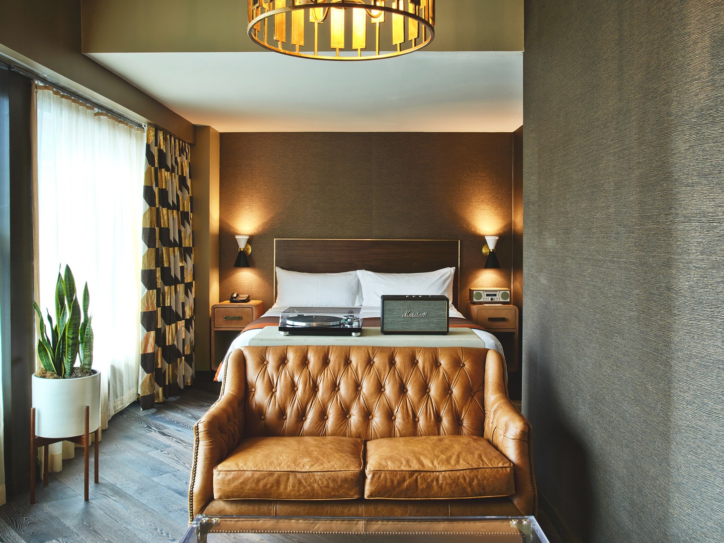 Loft suite bedroom with a king size bed and a leather couch. There is a marshall speaker and turntable sitting on the bed