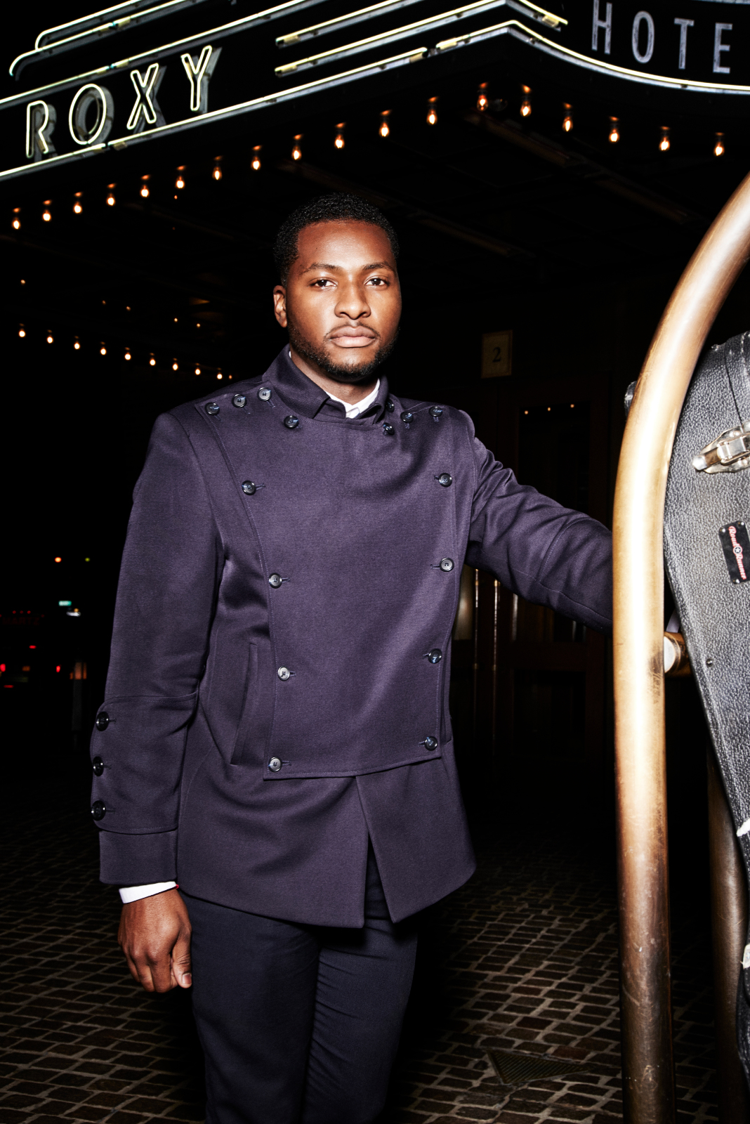 A young man in a bellman uniform standing underneath the Roxy Hotel marquee