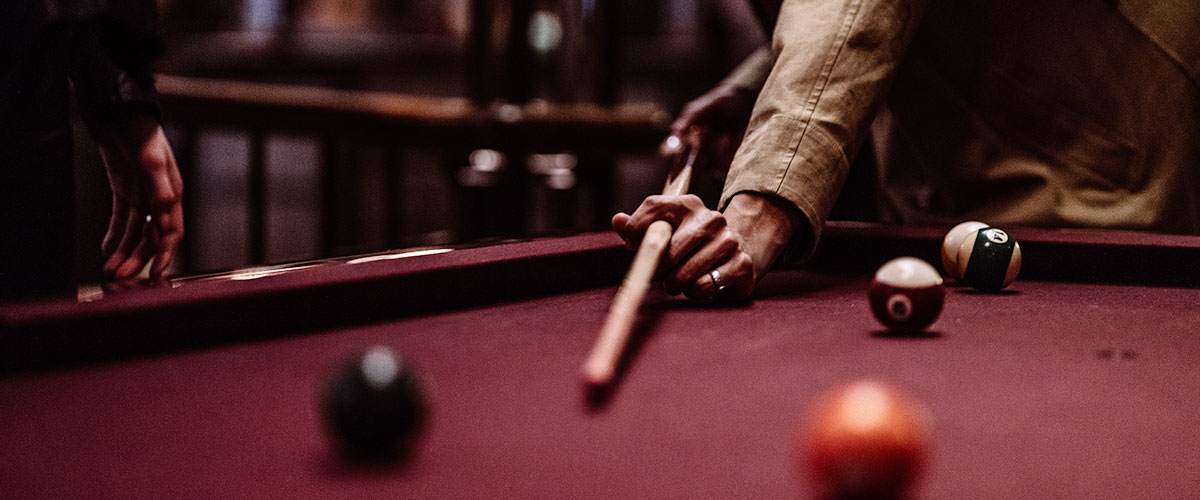 a detail shot of a man playing pool at the Roxy Bar