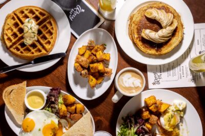 Brunch entrees including pancakes, eggs, waffle, and potatoes at Roxy Hotel.