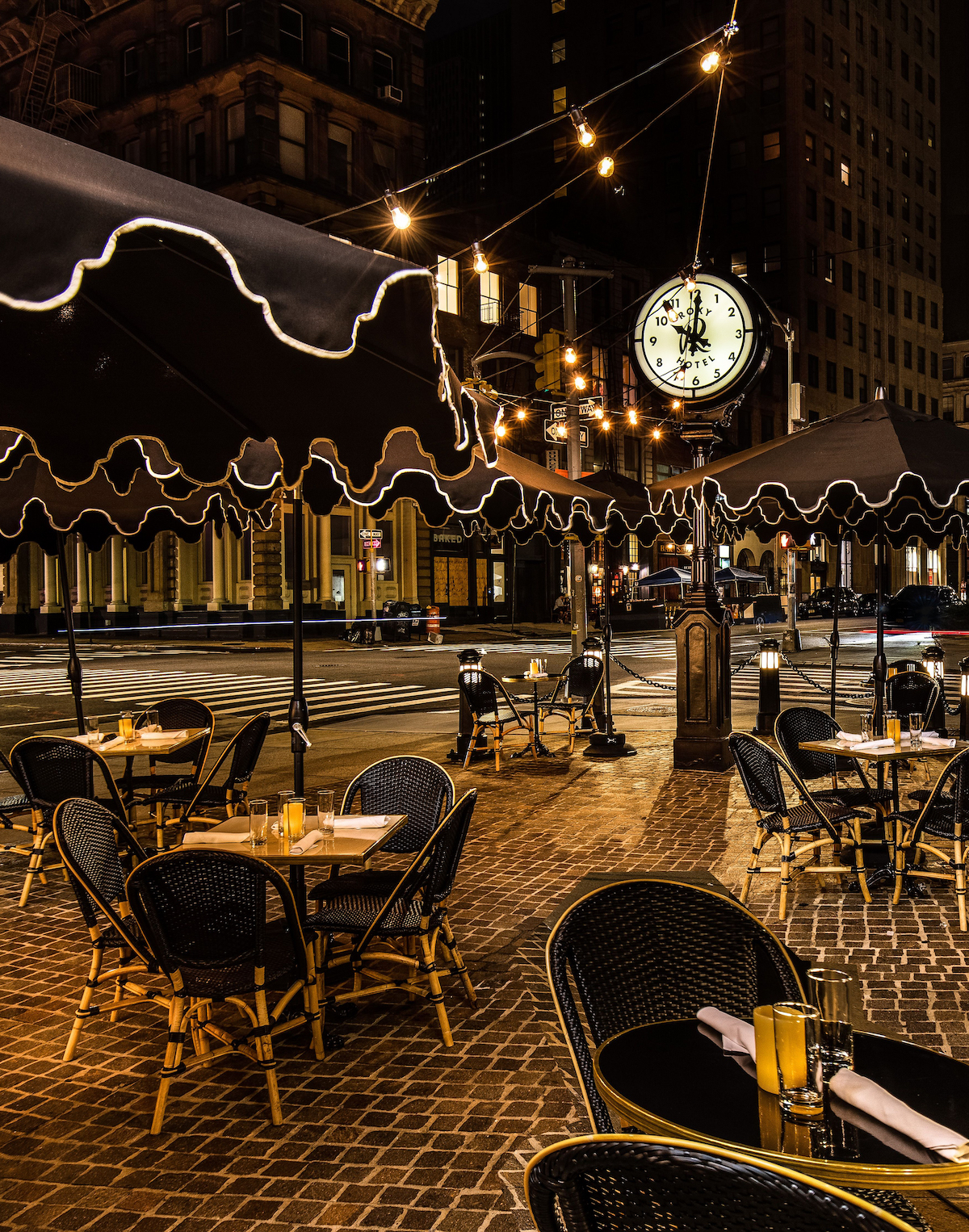 the roxy plaza at night. the clock tower sits in the center of the tables