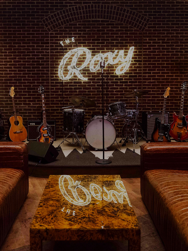 The Roxy Bar stage with guitars and a drum set sitting on stage