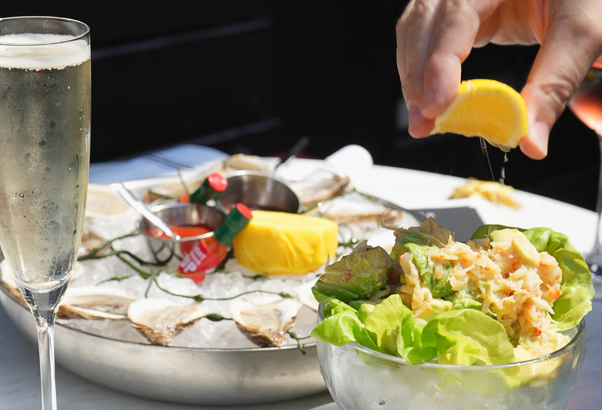 Man squeezing lemon on seafood salad at Roxy Cafe.