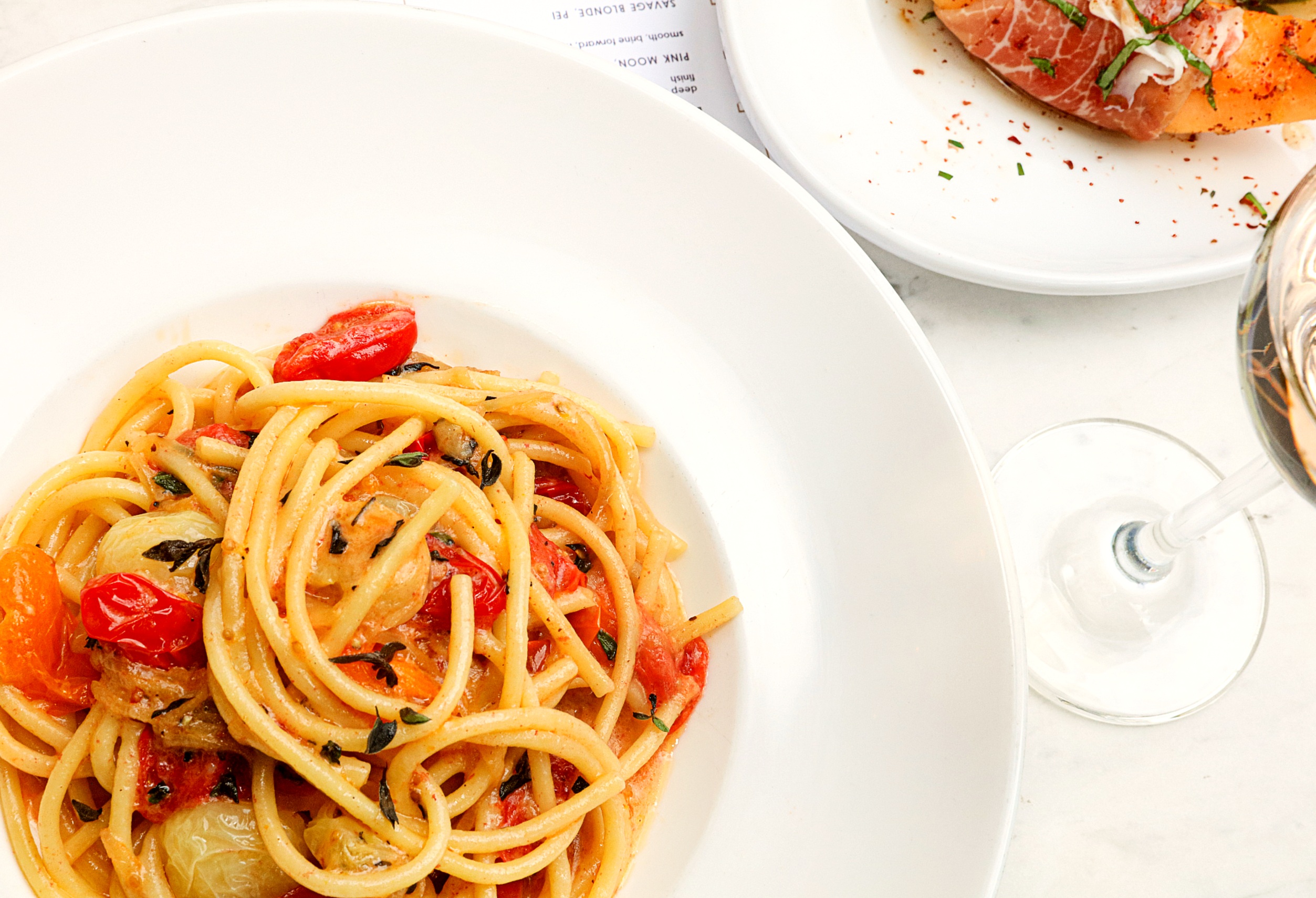 Spaghetti with tomatoes on a white dish.