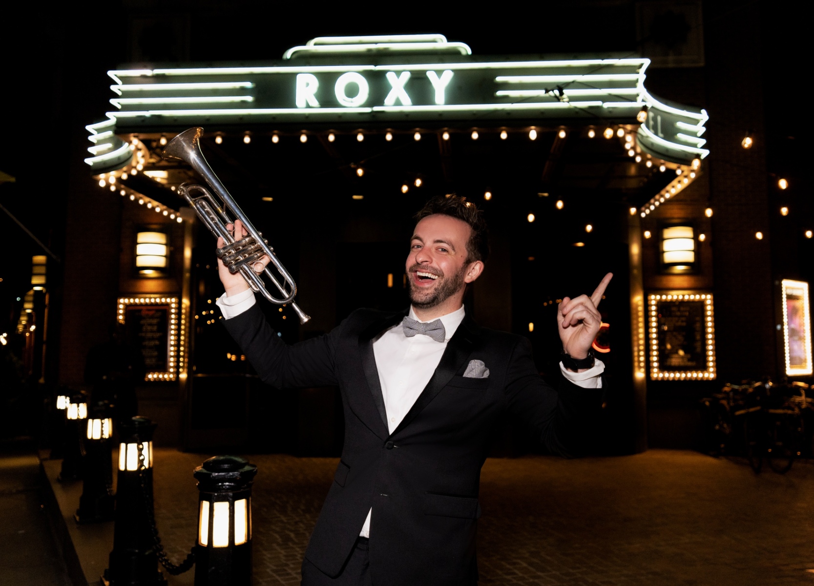 Trumpeter in a tuxedo under the Roxy Hotel Neon Marquee.