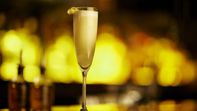 A detail shot of a Roxy Bar cocktail in a flute glass with a lemon twist.
