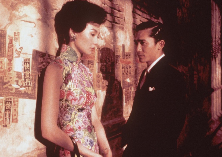 a man and a woman stand leaning against a wall. the woman looks down with the man stares at her longingly